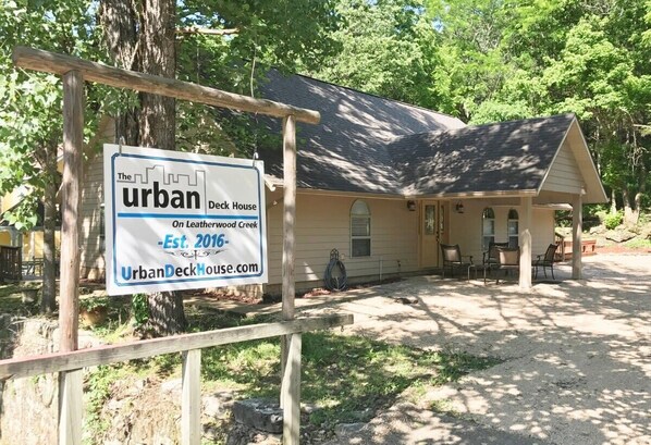 Señal de madera que indica 'The Urban Deck House' en Leatherwood Creek, establecida en 2016.