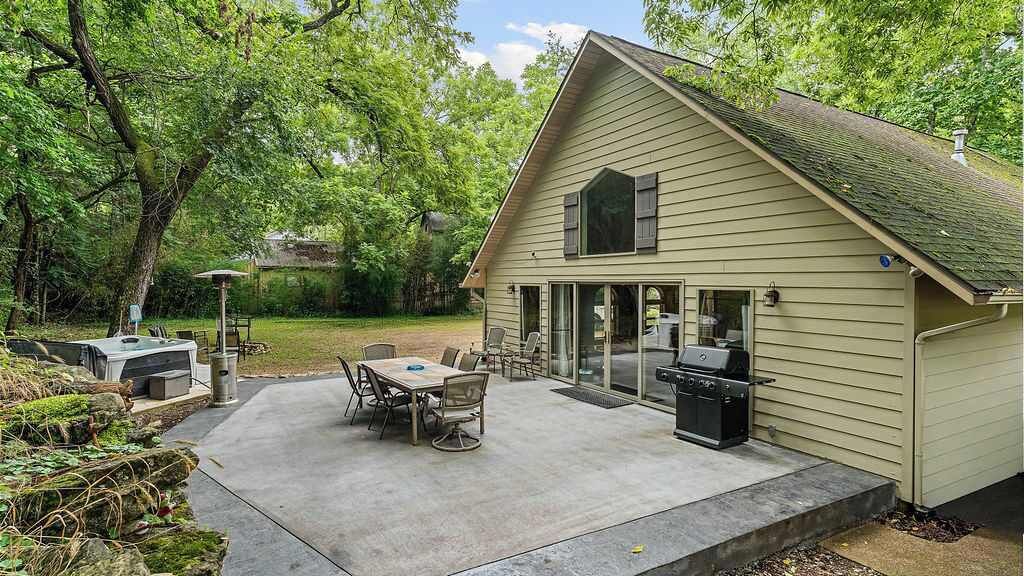 Ein Haus mit überdachter Terrasse, Grillplatz und einem Tisch mit Stühlen.