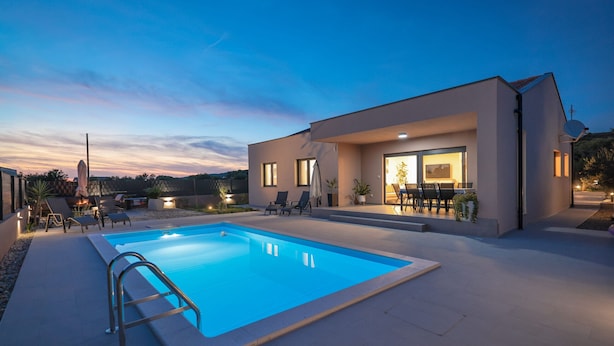 Ein modernes Haus mit Swimmingpool, Sitzgelegenheit im Freien und einer Terrassenfläche.