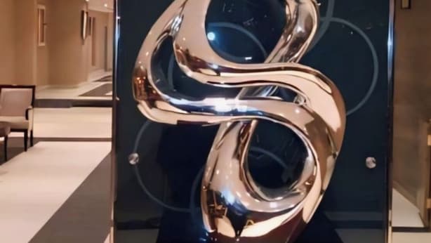 Eine moderne Skulptur in einer Lobby mit Glaswand und einer Holzplattform.