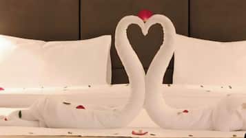 A bed with white linens and a heart-shaped decoration made from fabric.