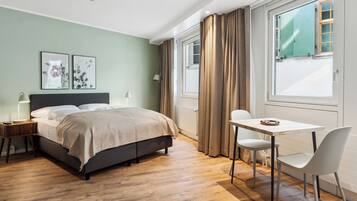 A modern bedroom with a bed, bedside tables, a desk, and a chair.