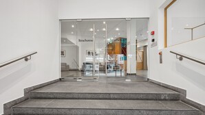 A modern interior with a staircase leading to a glass door labeled "limehome". - Limehome Basel Town Hall (Basel)