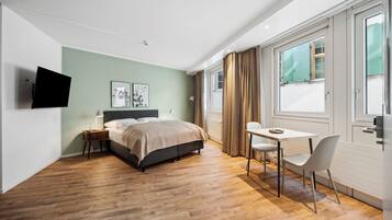 A modern bedroom with a bed, bedside table, and a TV mounted on the wall.