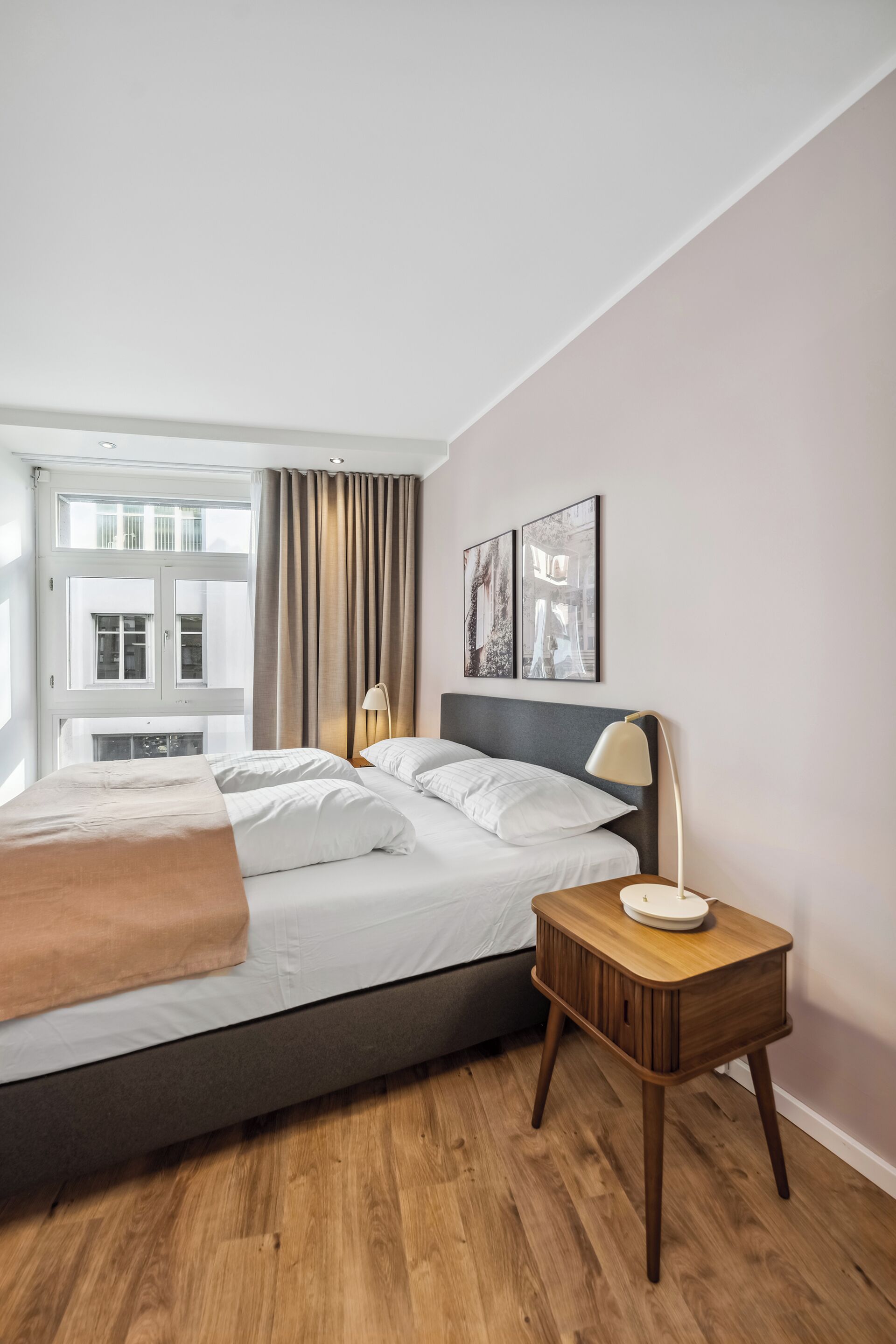 A modern bedroom with a bed, bedside table, lamp, and artwork on the wall.