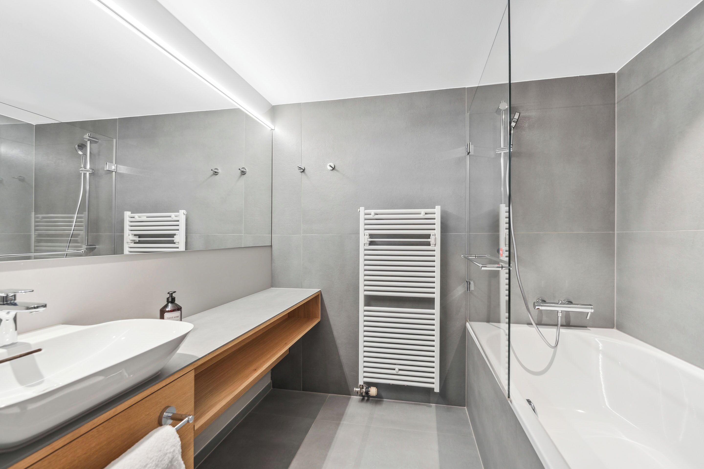 A modern bathroom with a large white sink, a bathtub, and a glass shower enclosure.