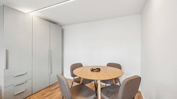 A modern conference room with a round table, four grey chairs, and a white cabinet with drawers.