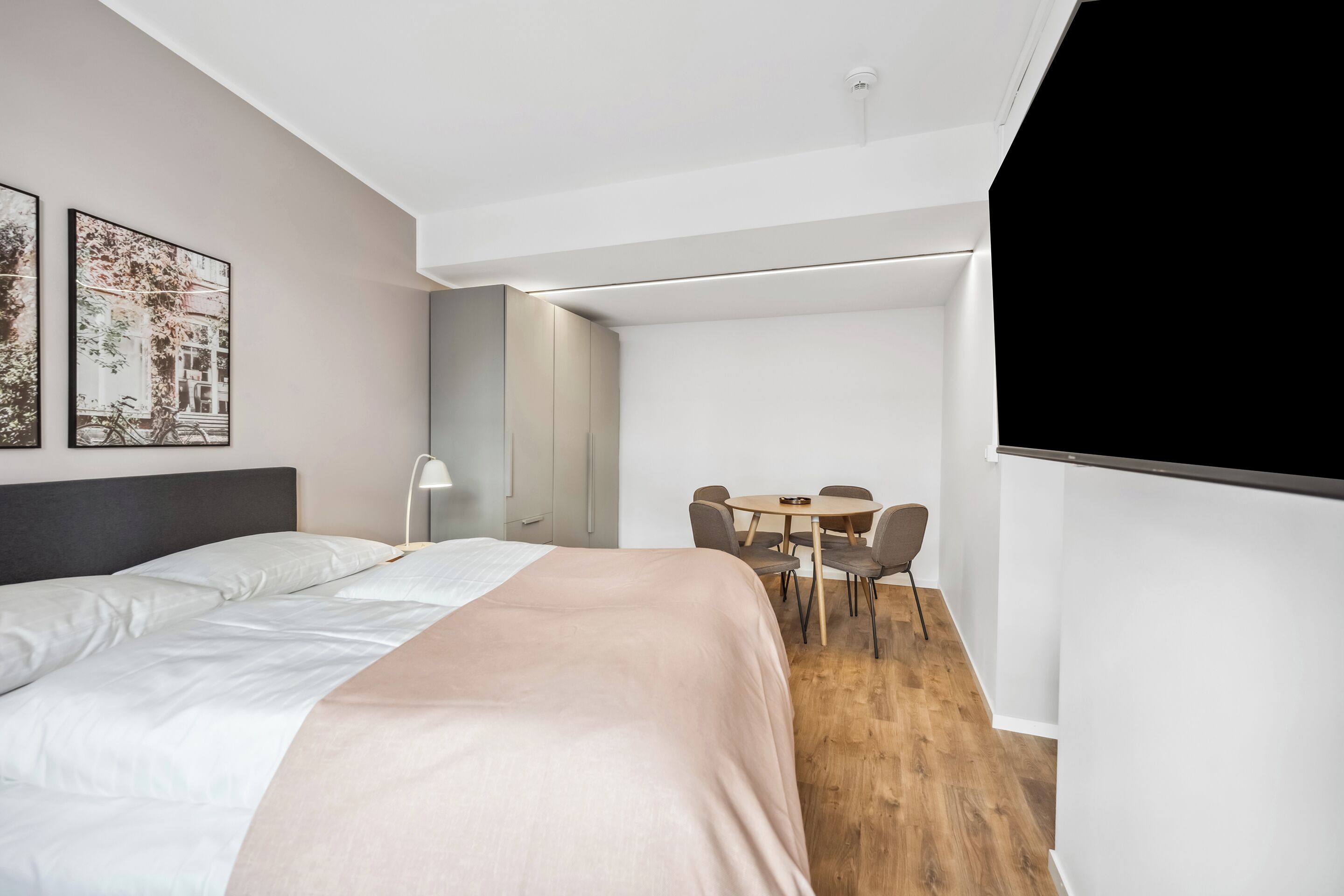 A modern hotel room with a bed, a desk, and a chair.