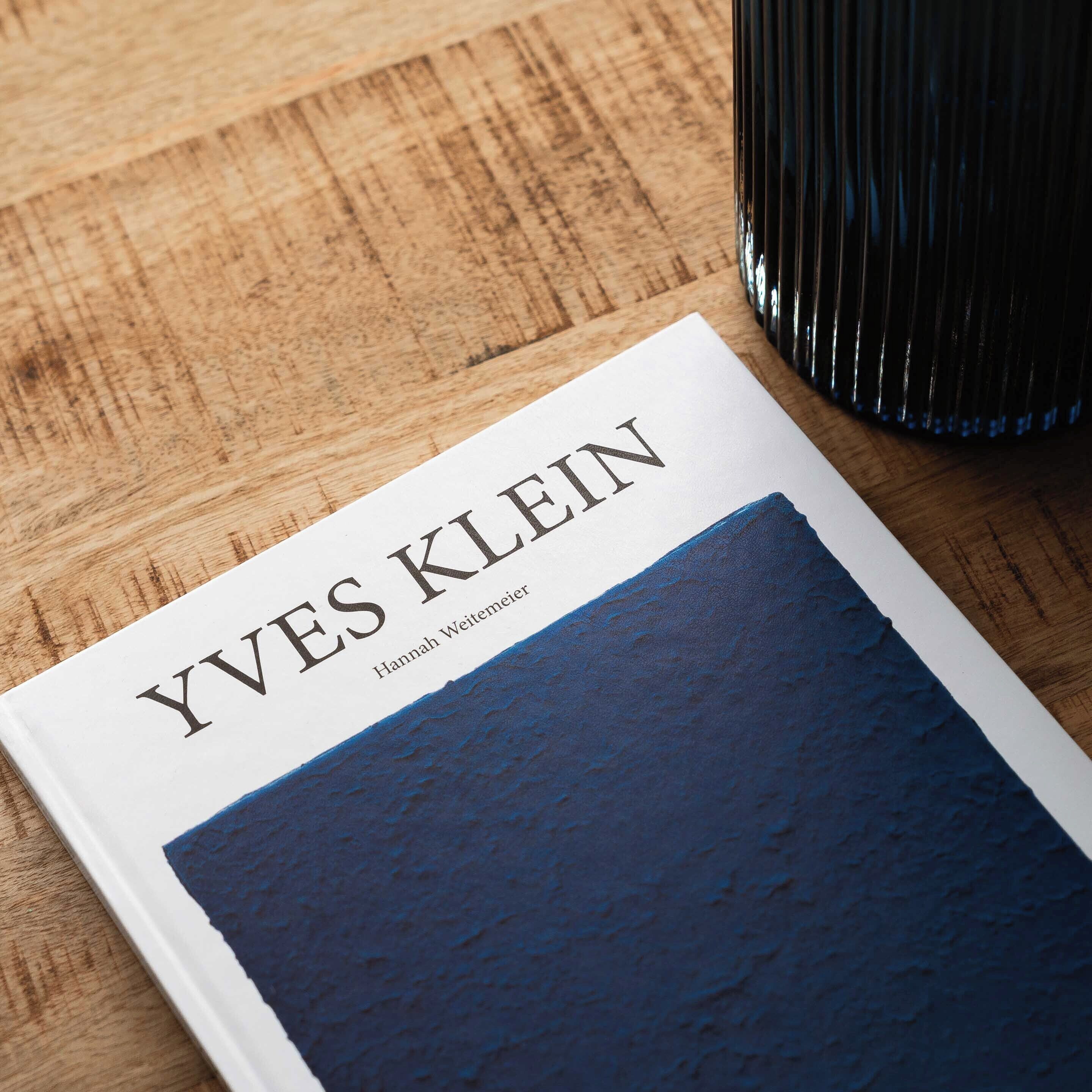 A book titled 'YVES KLEIN' by Hannah Weitemeyer on a wooden surface.