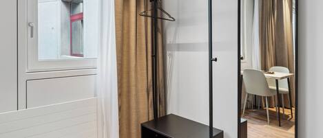 A modern room with a wooden floor, a black desk, a mirror, and a window with curtains.
