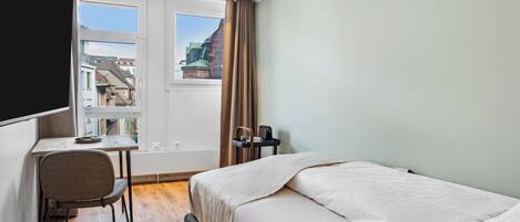 Una habitación de hotel con una cama, un escritorio y una silla.