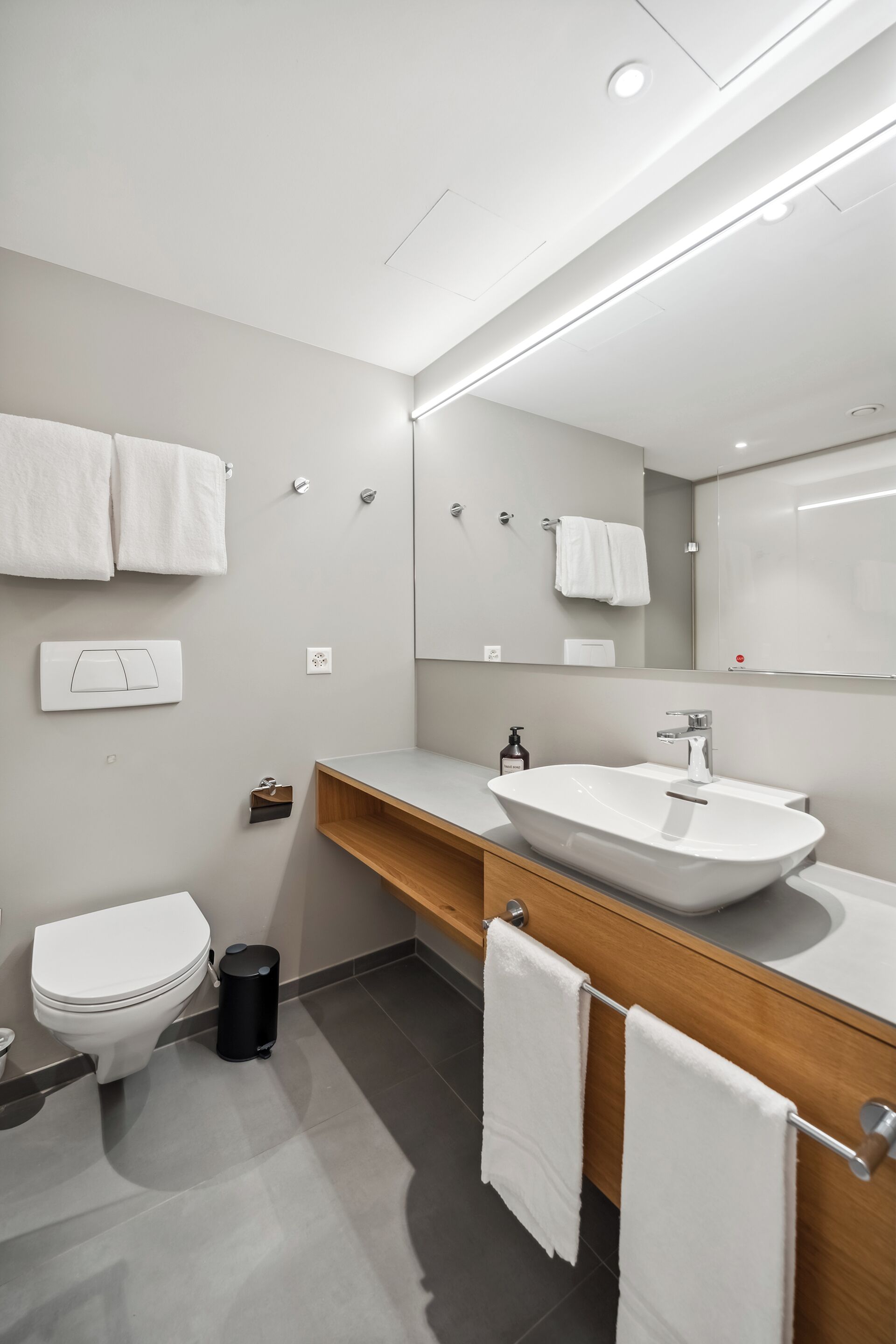 Un bagno moderno con lavandino, specchio e WC bianchi.