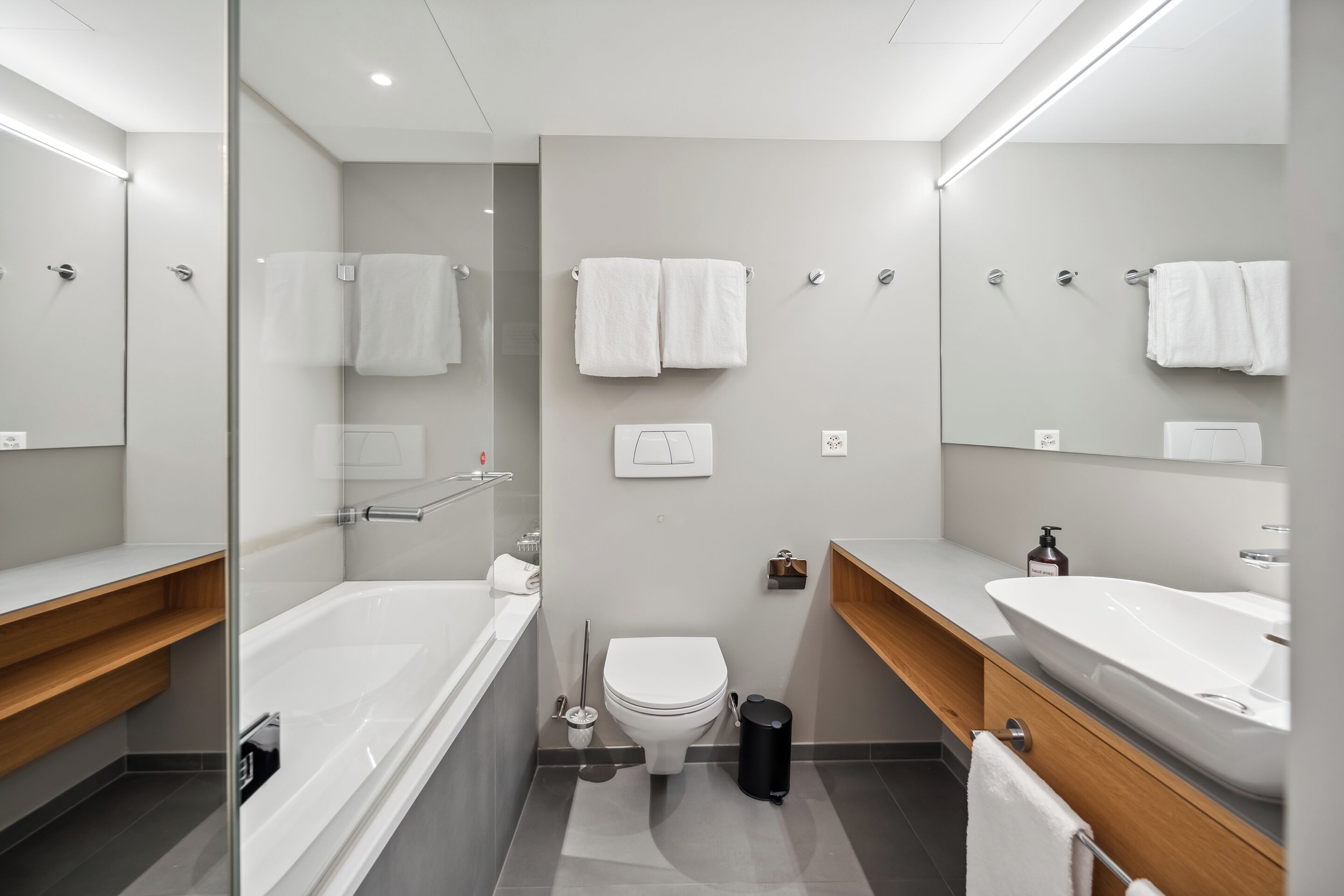 A modern bathroom with a bathtub, toilet, and two sinks.