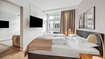 Una habitación de hotel moderna con una cama grande, un televisor de pantalla plana en la pared y obras de arte sobre la cama.