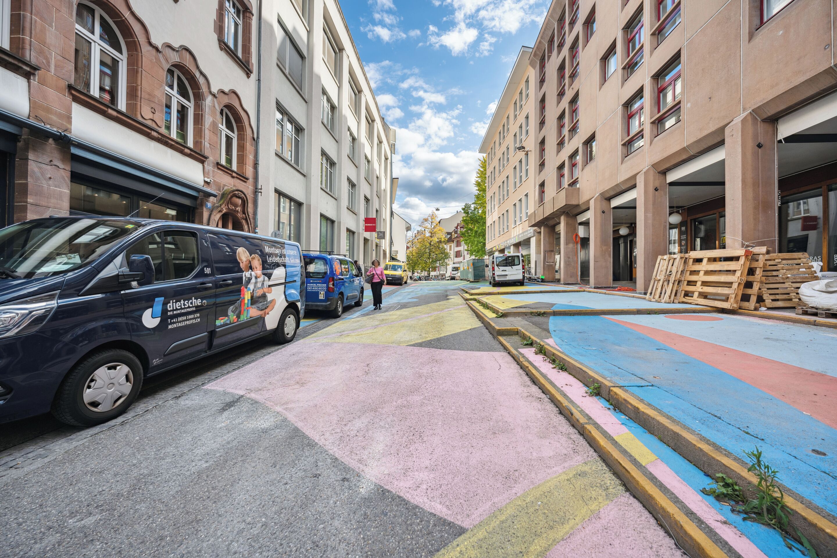 A street with parked vehicles and buildings.