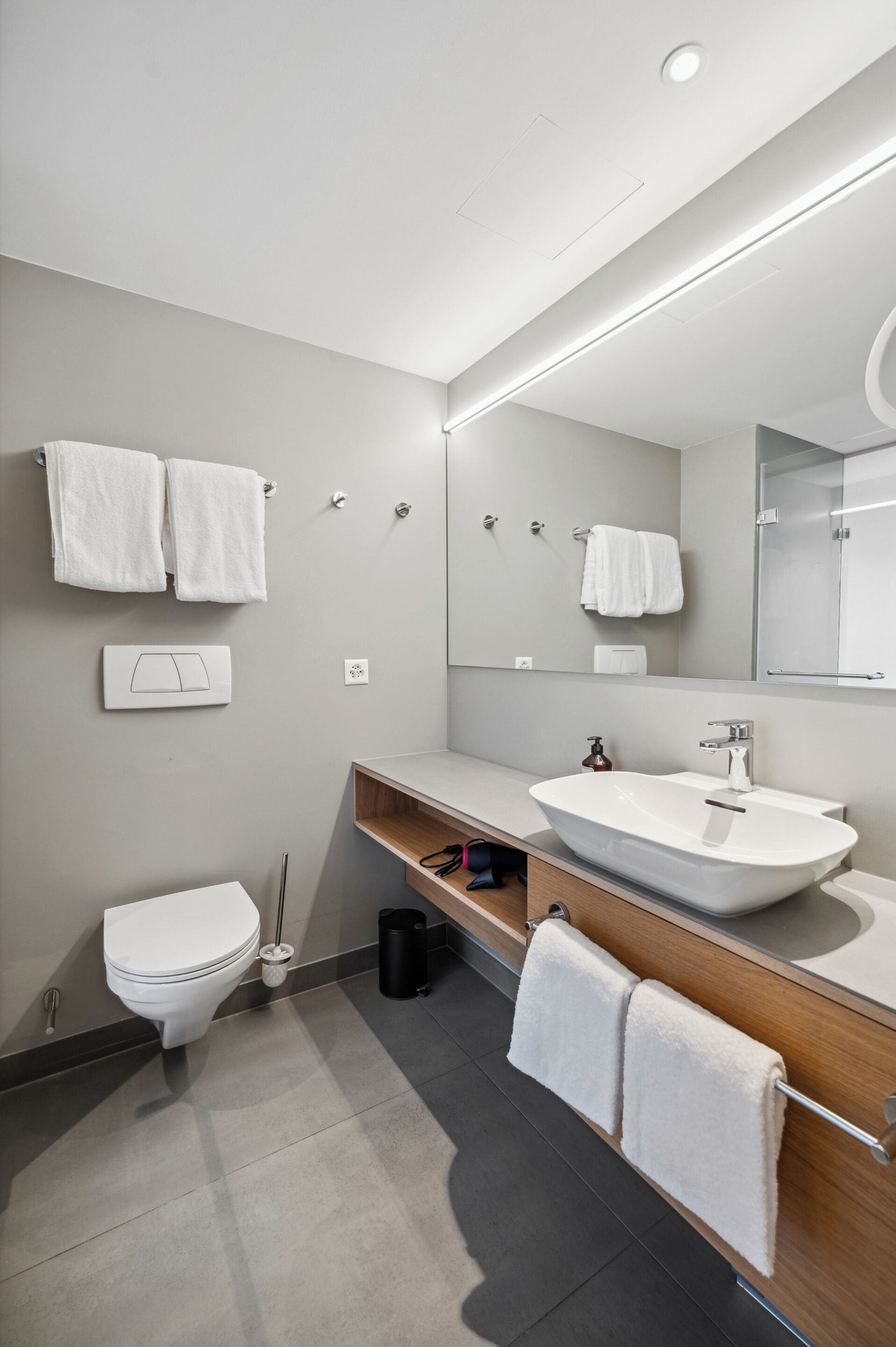 A modern bathroom with a toilet, sink, and mirror.