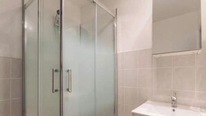 A modern bathroom with a glass shower enclosure, a white sink, and a mirror above the sink. - Apple blossoms (Les Moutiers-en-Cinglais)
