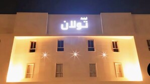 A building with illuminated windows and a sign in Arabic.