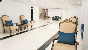A spacious lobby with a polished floor, a reception desk, and seating areas with upholstered chairs and a sofa.