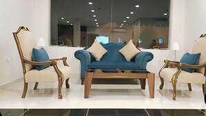 A modern living room with a blue sofa, two armchairs, and a coffee table.