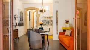 A modern living room with a sofa, a dining area with a table and chairs, and a kitchen in the background. - Ortigia Courtyard Apartment (Syracuse)