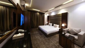 Et moderne hotelværelse med en stor seng, en sofa, et fjernsyn og et skrivebord med telefon og en æske.