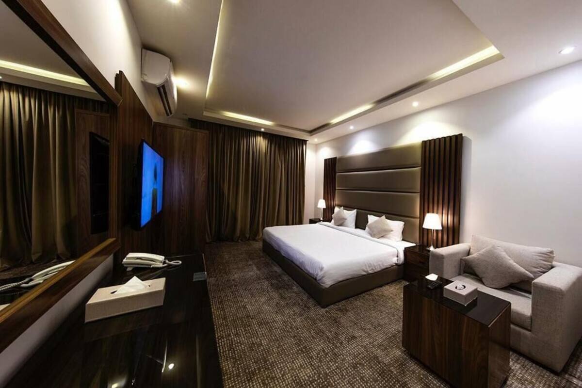Una habitación de hotel moderna con una cama grande, un sofá, un televisor y un escritorio con un teléfono y una caja.