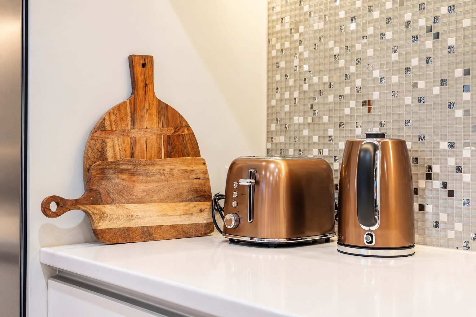 A kitchen counter with a wooden cutting board, a toaster, and a kettle.