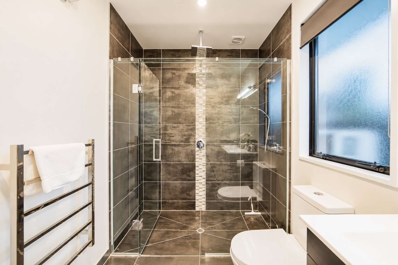 Ein modernes Badezimmer mit einer gläsernen Duschkabine, einer Toilette und einem Waschbecken.