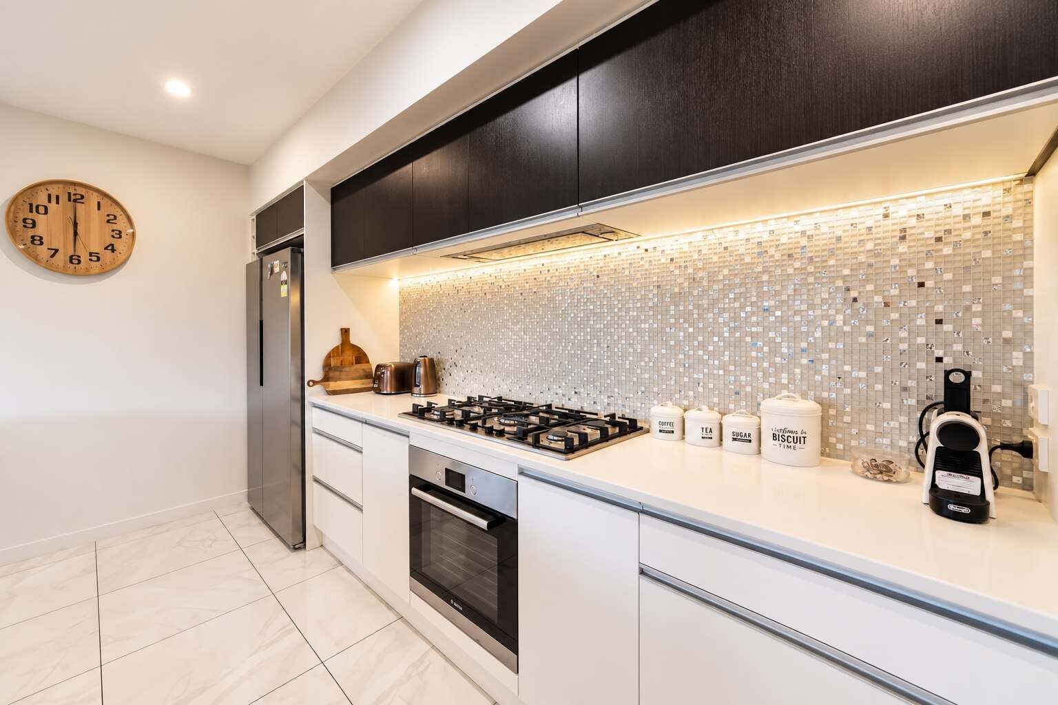 A modern kitchen with a gas stove, oven, and a coffee machine.