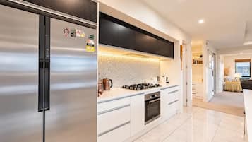 A modern kitchen with a stainless steel refrigerator, a gas stove, and white cabinetry.