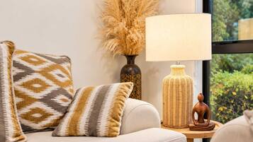 A sofa with patterned cushions, a wicker lamp, and a vase with dried plants.