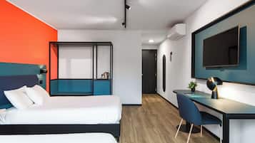 A modern hotel room with a bed, a desk, and a TV.