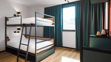 Camera con letto a castello, pavimento in legno, finestra con tende e un tavolino con bollitore.