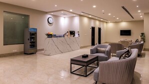 A modern lobby with a reception desk, seating area, and a clock on the wall. - Towlan Qurtuba 2 Serviced Apartments (Riyadh)