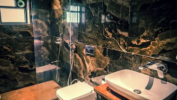 A bathroom with a marble wall, a white sink, and a shower area.