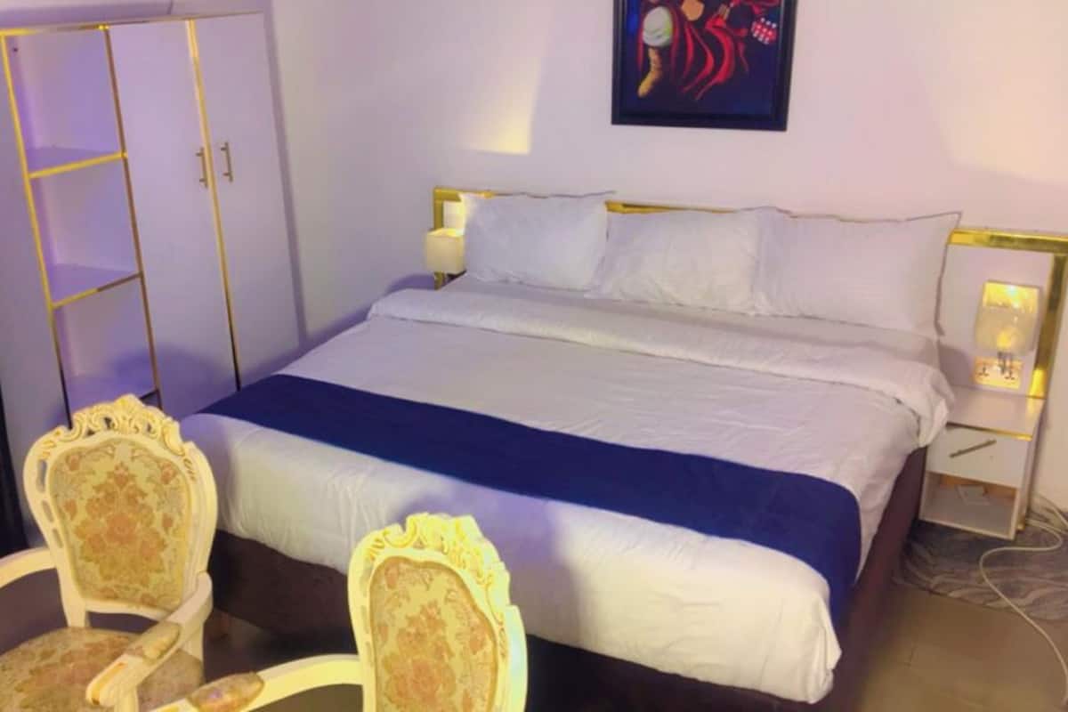 Ein Hotelzimmer mit einem großen Bett, zwei Nachttischen, einem Sessel und einem Kleiderschrank.