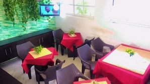 A dining area with tables covered in red tablecloths, chairs, and a television screen mounted on the wall. - Autograph Apartment (Lagos)