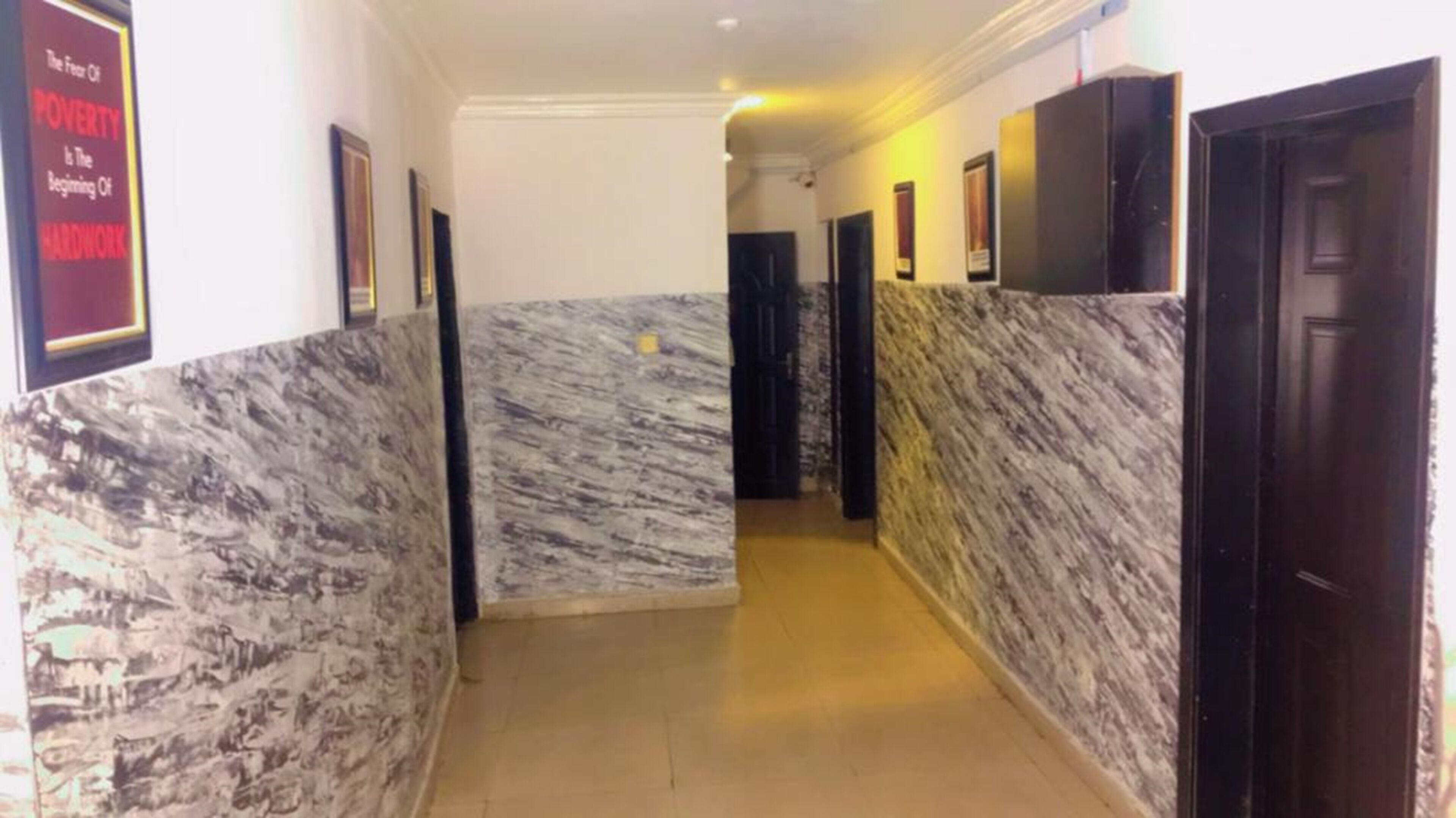A hallway with marble walls and doors, leading to rooms.