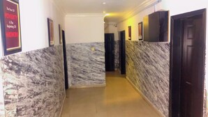 A hallway with marble walls and doors, leading to rooms. - Autograph Apartment (Lagos)