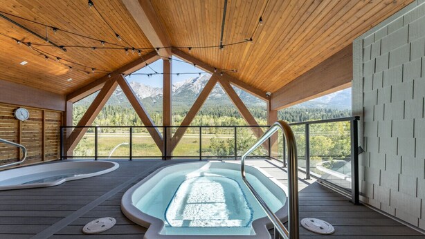 Terraza de madera con un jacuzzi y vistas a las montañas.