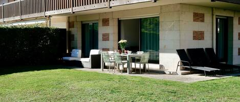Un hotel con balcón, mobiliario exterior y un césped bien cuidado.