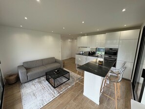 A modern kitchen with white cabinets, a black countertop, and stainless steel appliances.