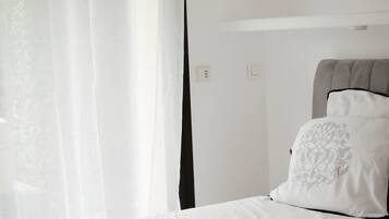 Une chambre à coucher avec un lit, des rideaux blancs et une tête de lit.