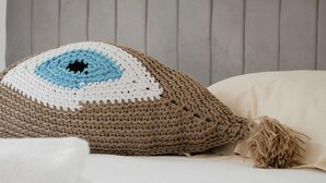 A bed with a grey upholstered headboard, a crocheted pillow with a blue and white pattern, and a white pillow. - Jardin privé + parking · 6 pers · plage 2 min (Deauville)
