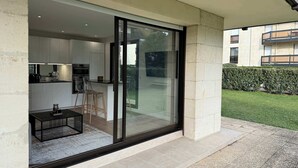 A modern kitchen with a glass door leading to a patio area. - Jardin privé + parking · 6 pers · plage 2 min (Deauville)
