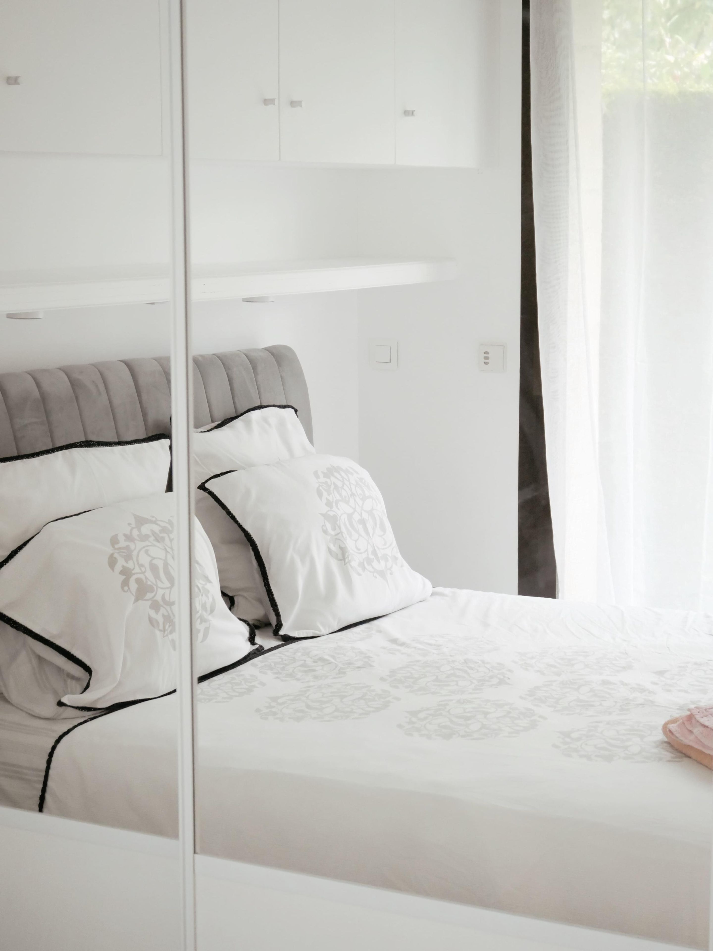 A bedroom with a bed, a wardrobe, and a mirror.