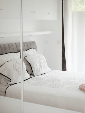 A bedroom with a bed, a wardrobe, and a mirror.