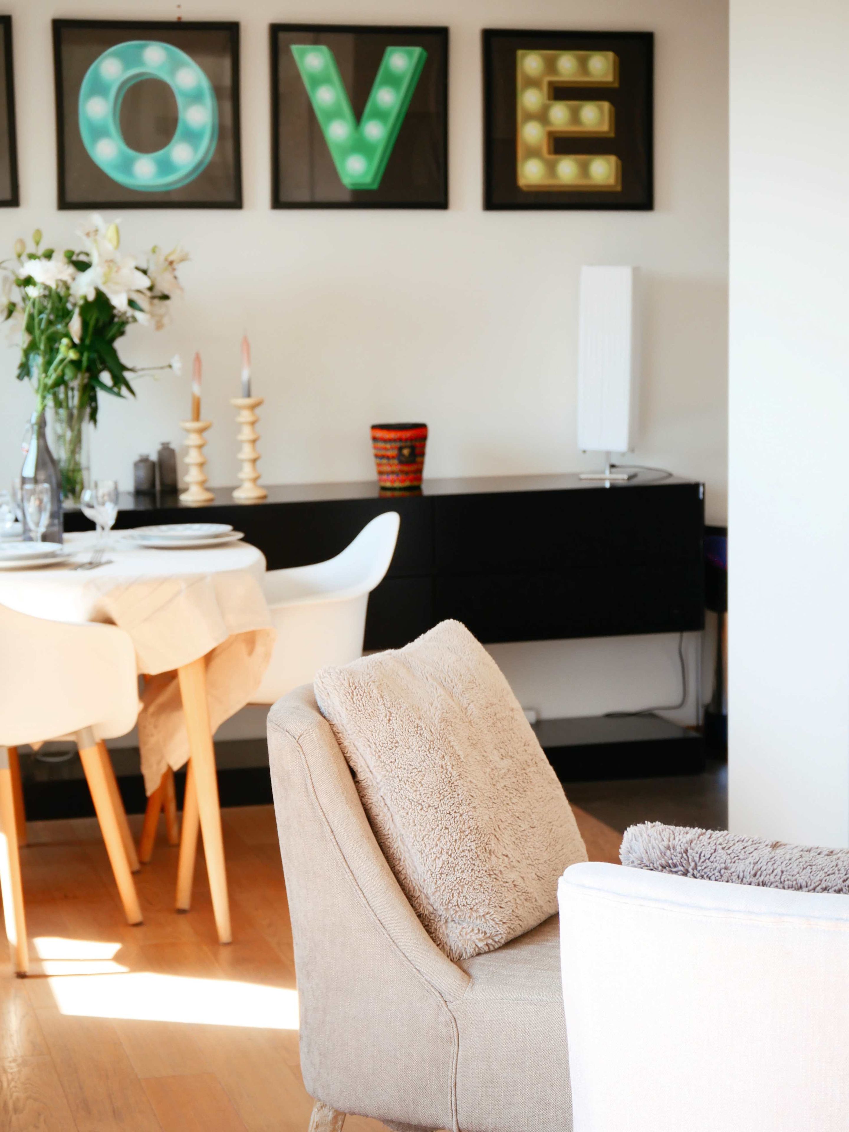 Een moderne woonkamer met een eethoek, voorzien van een piano, een witte bank en een gedekte tafel.