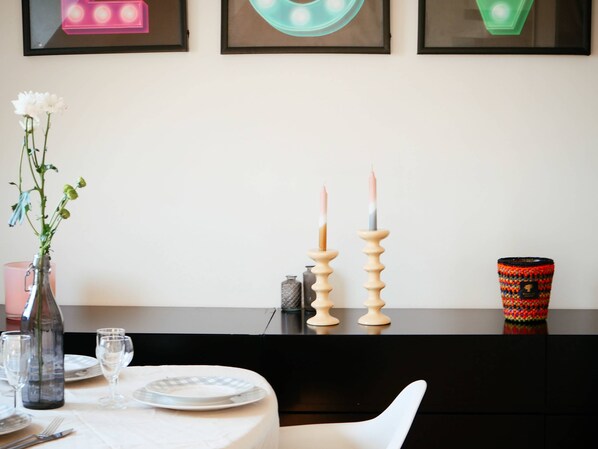 Una mesa de comedor preparada con platos, vasos y un florero con flores.